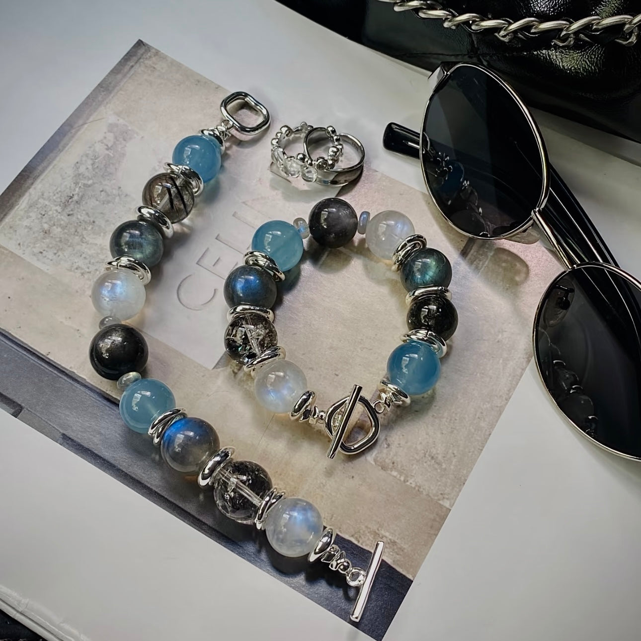 Close-up detail of Aquamarine, Moonstone, Herkimer Diamond, and Black Rutilated Quartz gemstones with premium silver-toned titanium steel hardware.
