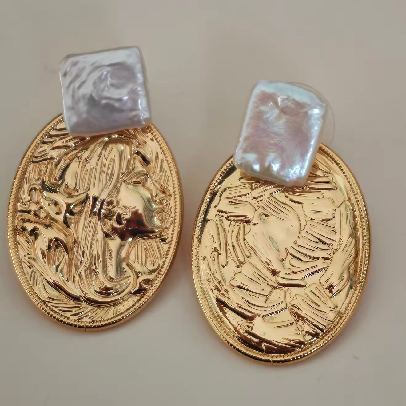 Close-up of the intricate copper relief and the iridescent luster of the square baroque pearl.