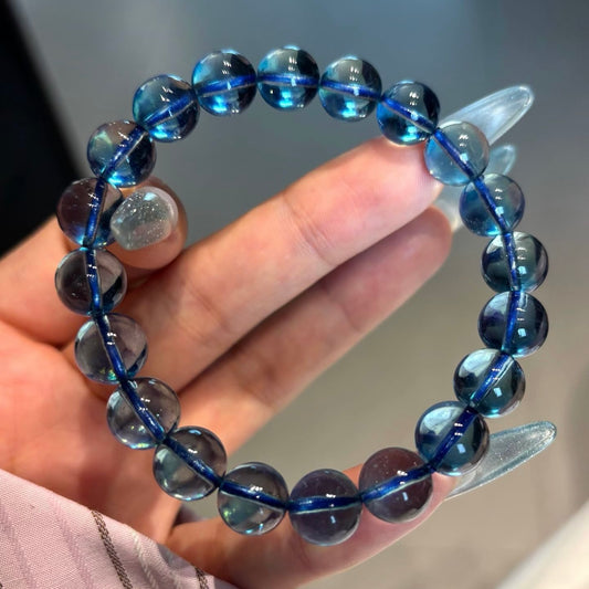 A side-back view of a closed hand showing high-definition, ice-clear natural aquamarine beads (10.2mm) aligned across the knuckles, emphasizing their flawless, glass-like clarity.