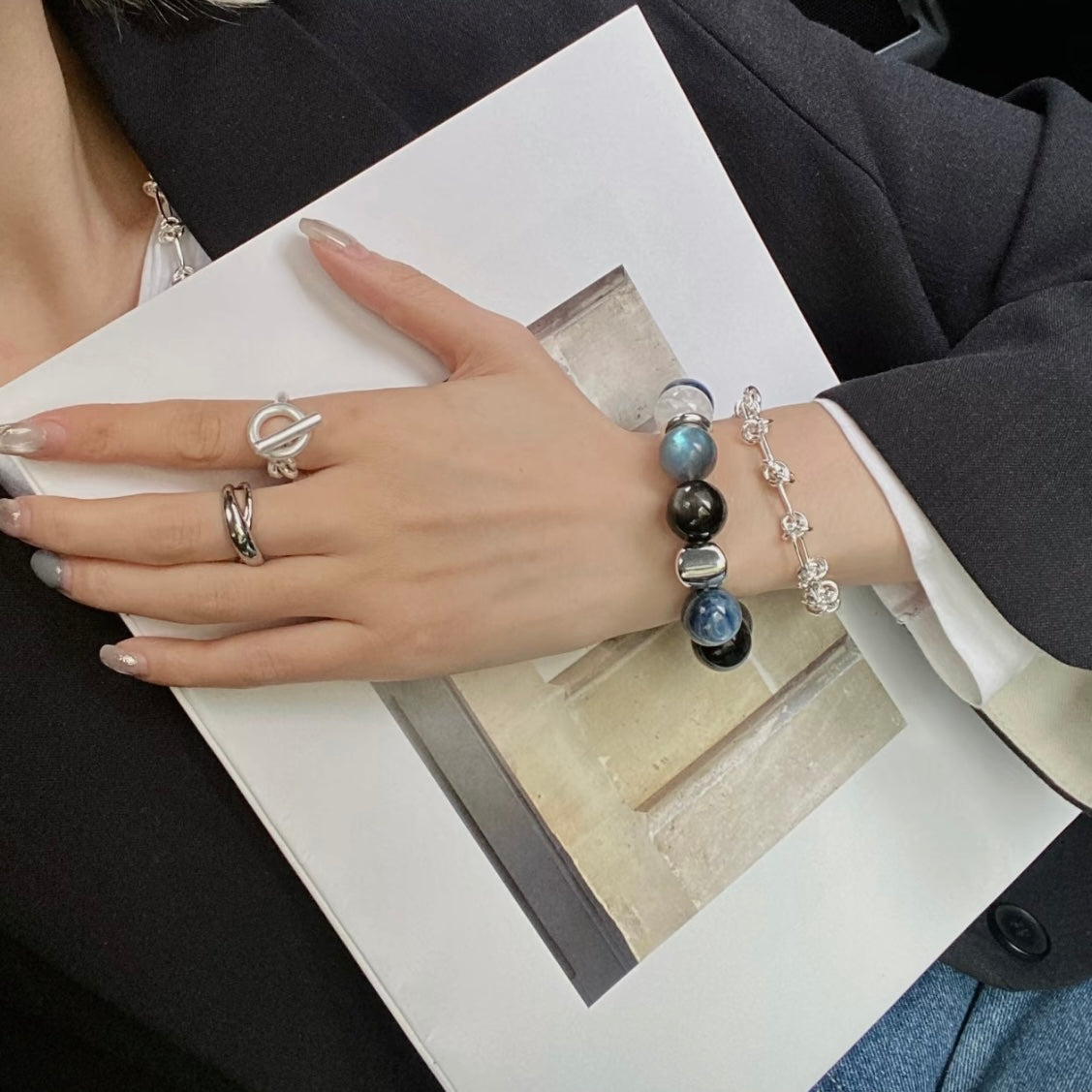 Lifestyle wrist shot of natural crystal bracelet set featuring kyanite, silver obsidian, grey moonstone and white snowflake phantom quartz