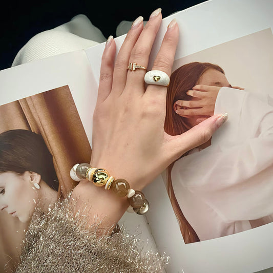 Model wearing stacked white snowflake phantom quartz and mother-of-pearl bracelet with moonstone and smoky quartz beads, wrist layering shot