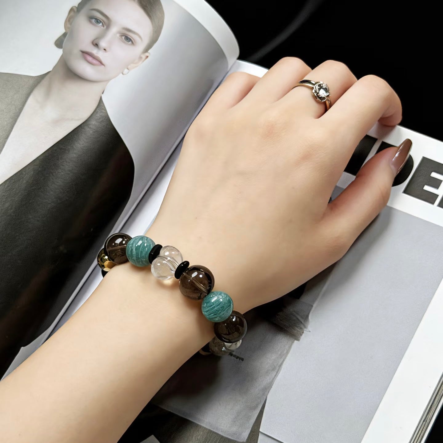 A hand holding the 15mm Amazonite and Smoky Quartz bracelet, showcasing the vivid sky-blue and deep tea-colored beads