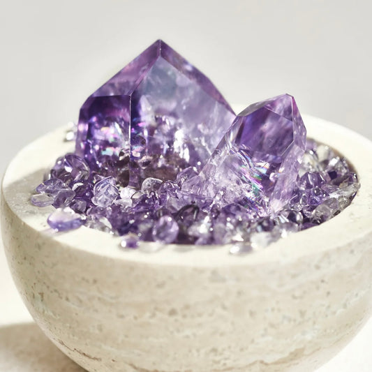 Top-down view of 3 random-shaped amethyst points paved with amethyst chips inside a stone vessel.