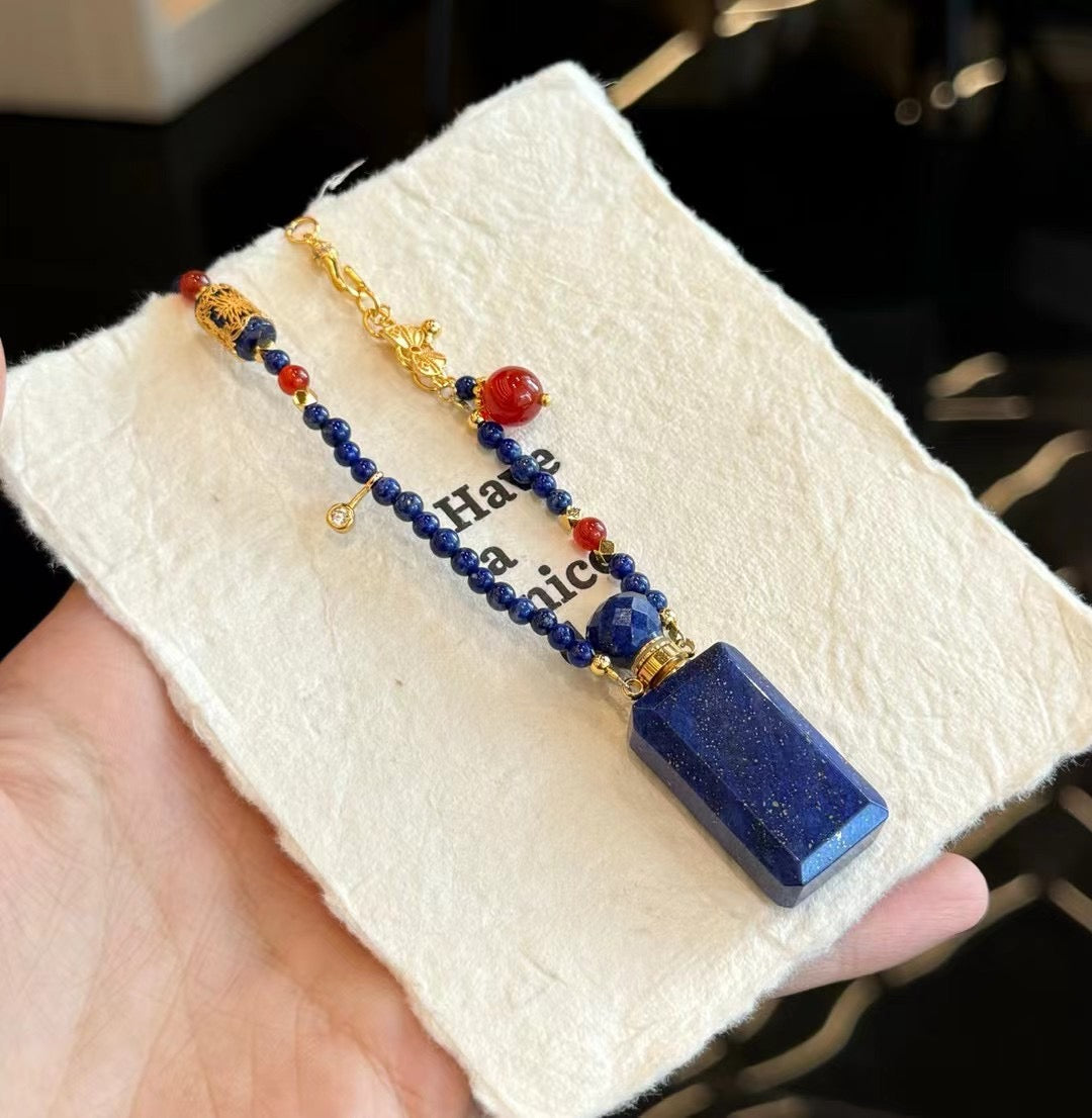 A serene flatlay of the lapis oil bottle necklace with dried petals and essential oils.