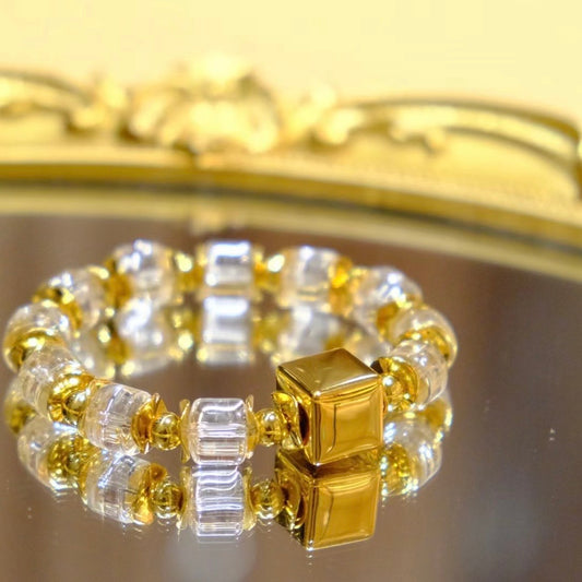 Minimalist geometric wheel bead clear quartz bracelet reflecting on a mirror surface.