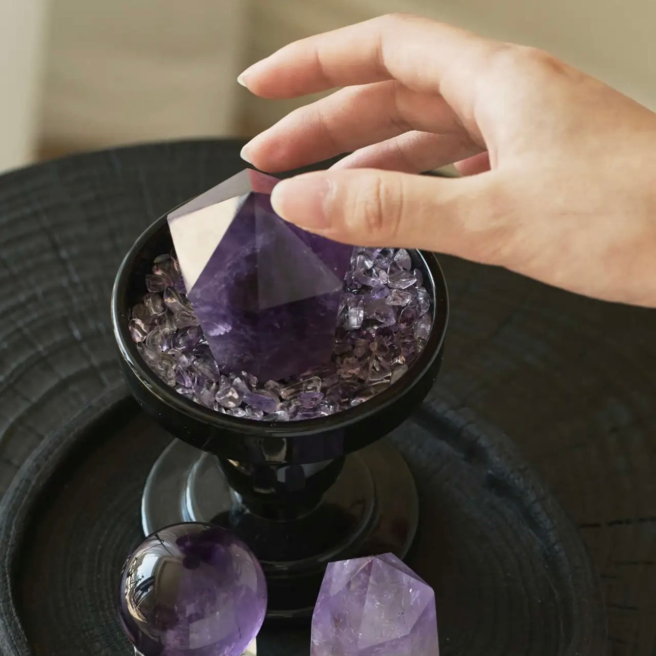 Placing amethyst points and chips onto the base tray, showing the process of creating an exclusive healing energy field