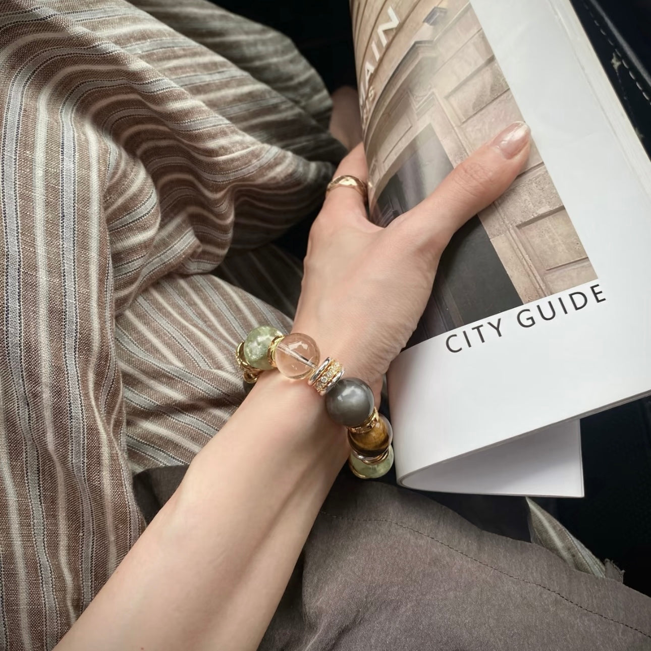 Hand model styling layered bracelet stack with old money aesthetic — natural green aventurine, moonstone and smoky quartz chunky stone bracelets with minimalist gold pieces