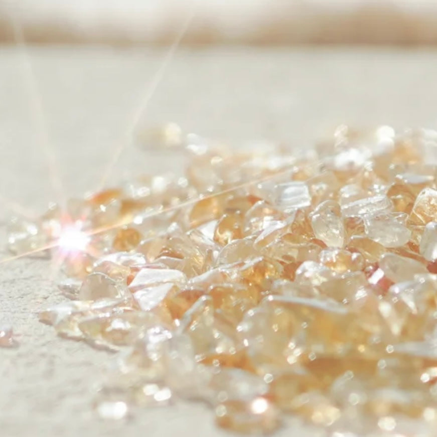 Vibrant Citrine natural crystal chips for attracting wealth and positive energy in a sleek glass vessel.