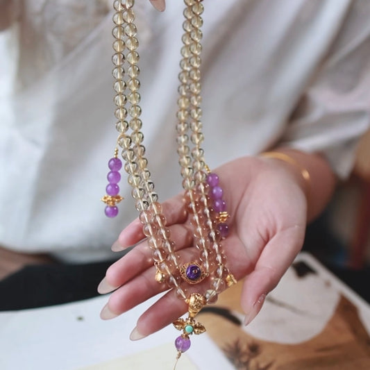 The citrine mala beads wrapped around a model's wrist as a bracelet during meditation.