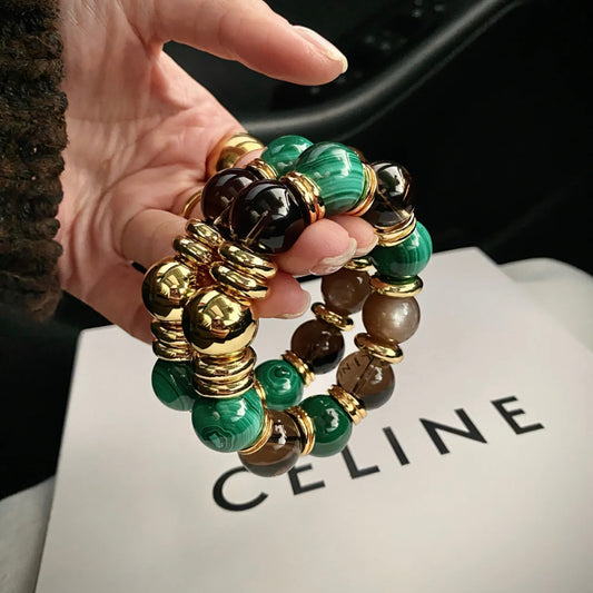 Detailed view of the natural malachite patterns and smoky quartz translucency with gold spacers.