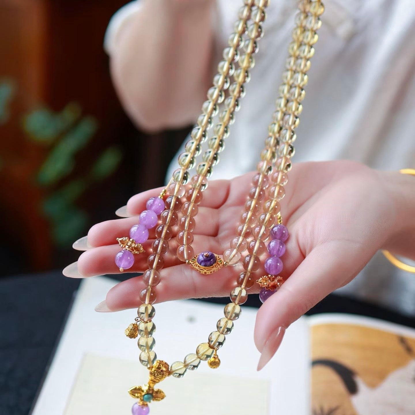 Close-up of a model's fingers moving through the hand-polished citrine beads.