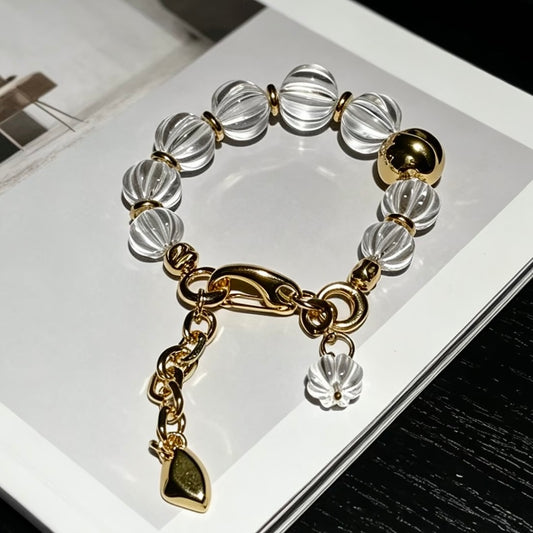 Architectural fluted clear quartz bracelet with bold 316 titanium steel gold hardware, styled on a fashion magazine.