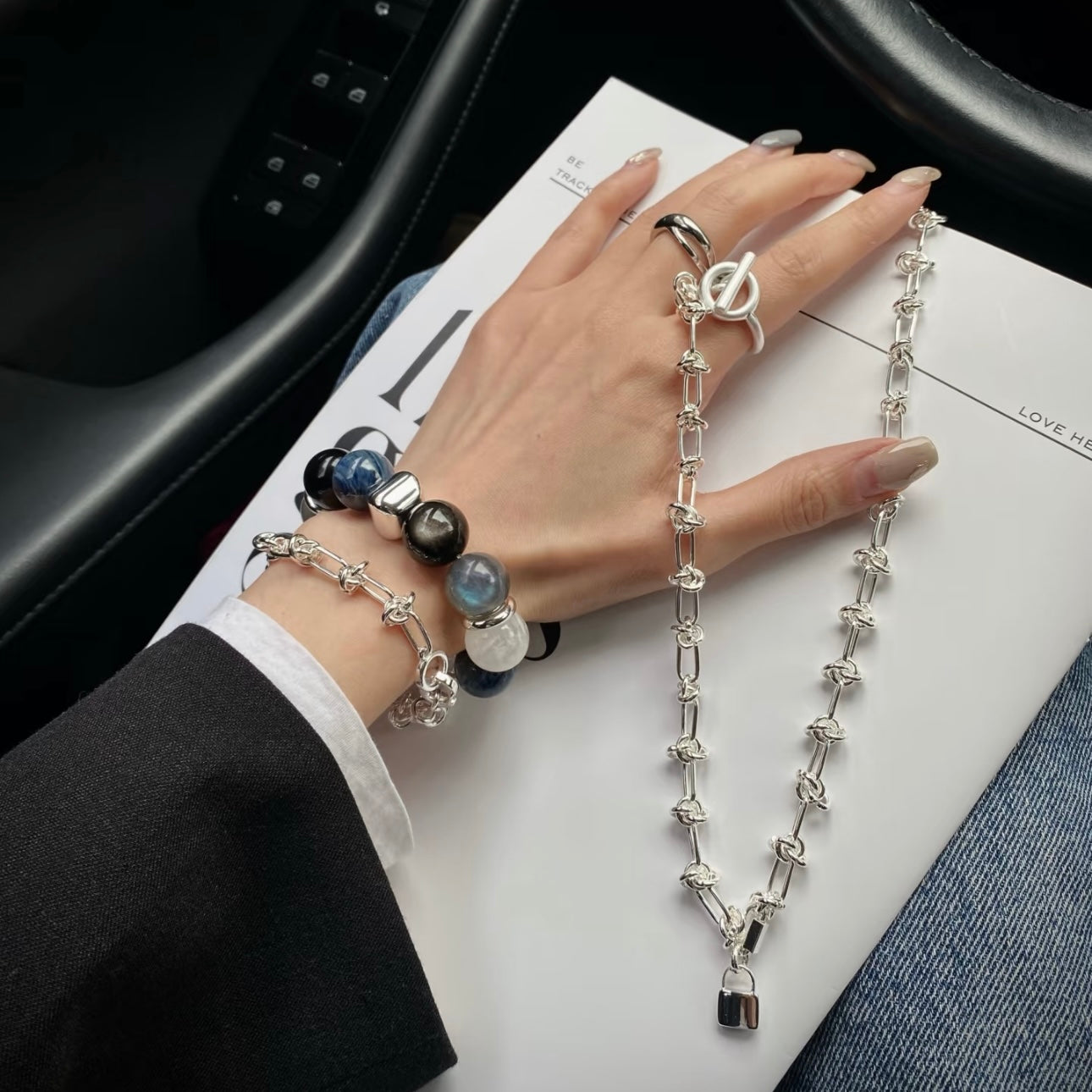 Model wearing stacked kyanite blue moonstone and white snowflake phantom crystal bracelet with silver titanium steel bracelet on wrist