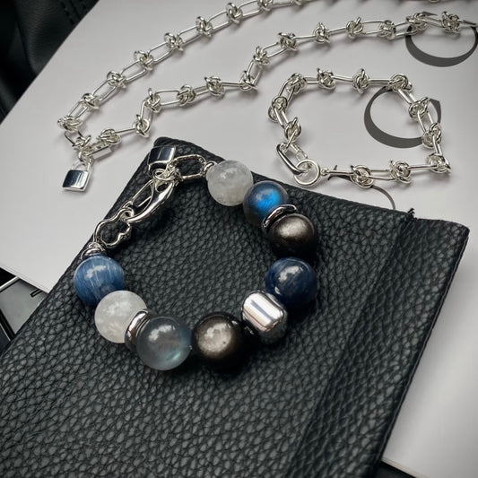 Kyanite, grey moonstone and white snowflake phantom quartz crystal bracelet set with silver titanium steel bracelet, flatlay on neutral background