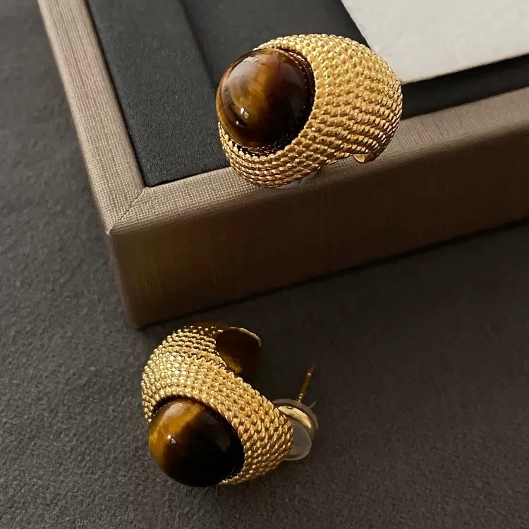 Close-up of the intricate woven metal texture and the silky light reflection on the natural tiger's eye gemstone.