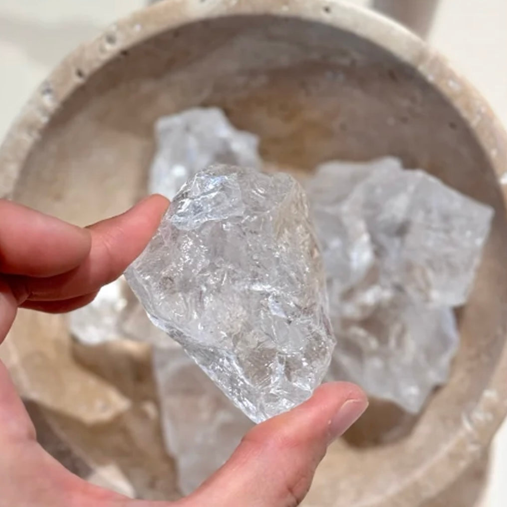 A hand holding a single natural Himalayan crystal to show its unique shape and pure transparency.
