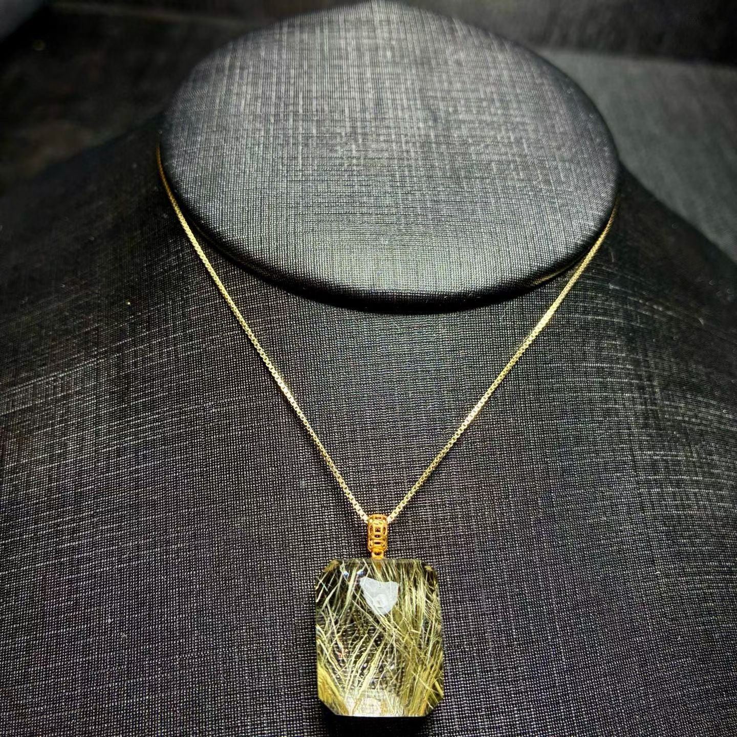 Luxury 18K gold inlaid natural golden rutilated quartz cube pendant on a black display.