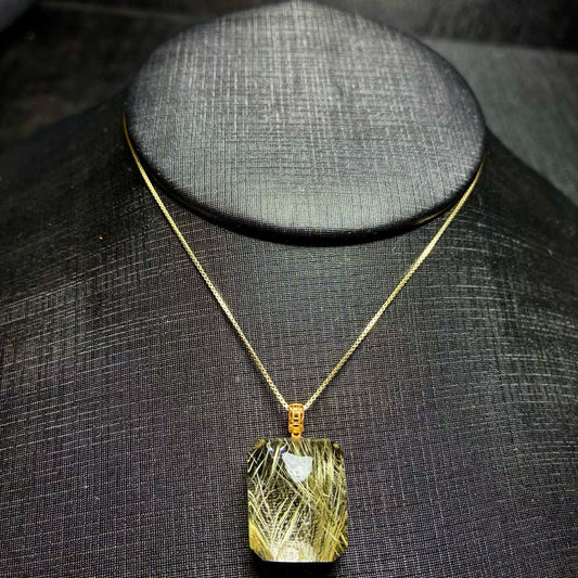 Luxury 18K gold inlaid natural golden rutilated quartz cube pendant on a black display.