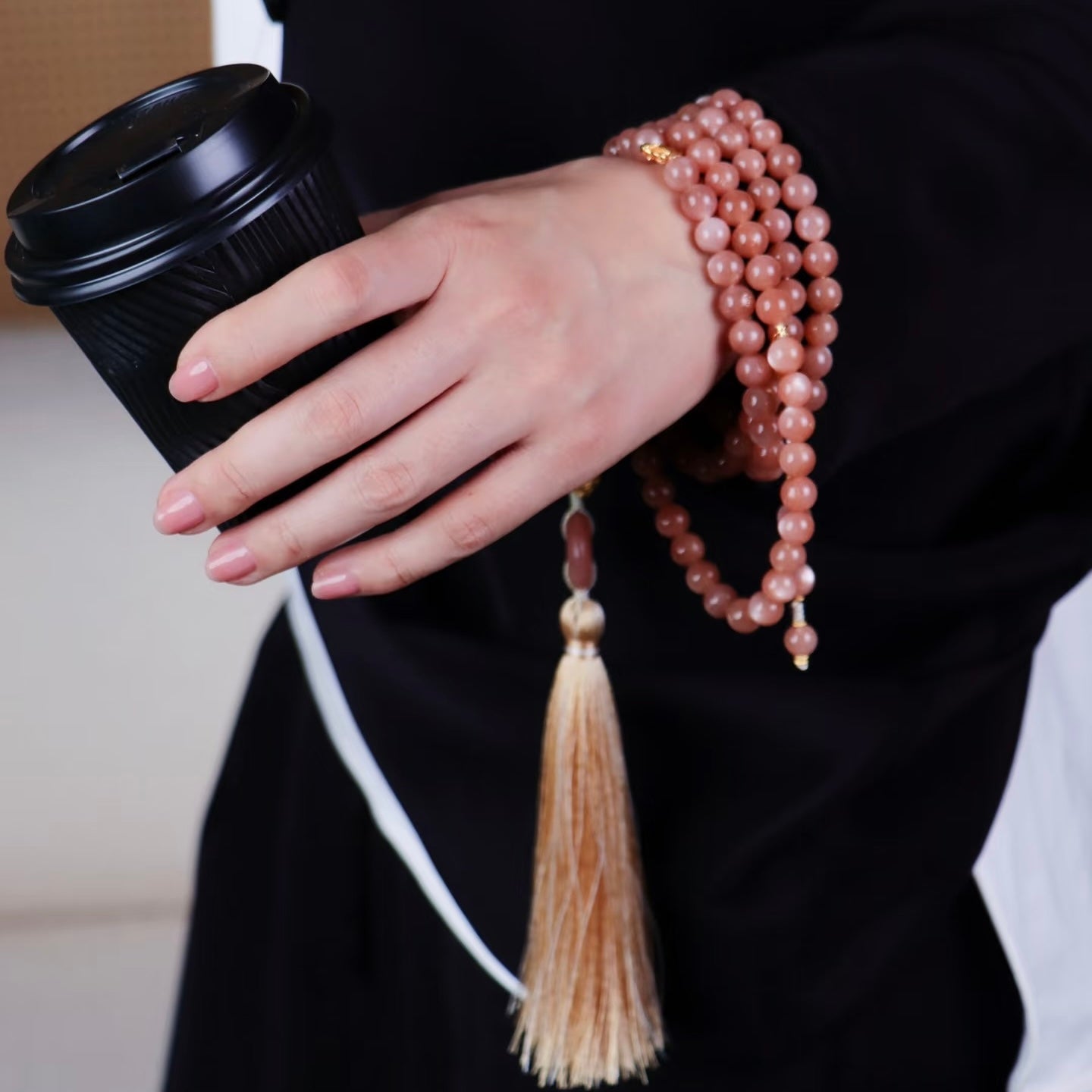 Close-up of a model's hand using the sunstone beads for mindful practice, illustrating its calming power.