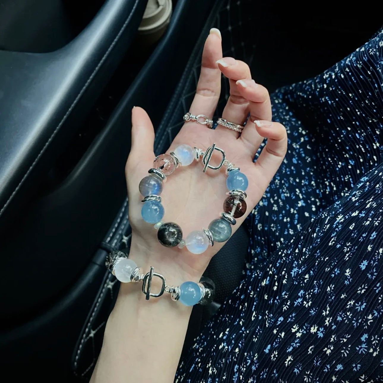 Close-up of a hand wearing an Aquamarine, Moonstone, and Black Rutilated Quartz bracelet, highlighting natural gemstone textures and modern jewelry craftsmanship.