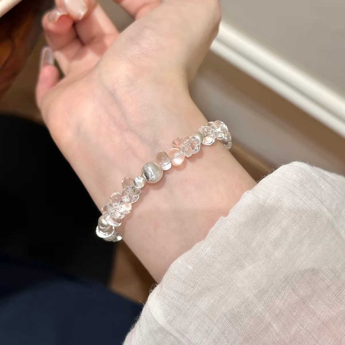 Woman wearing a white freeform clear quartz bracelet on its own, creating a clean minimalist jewelry look for everyday styling.