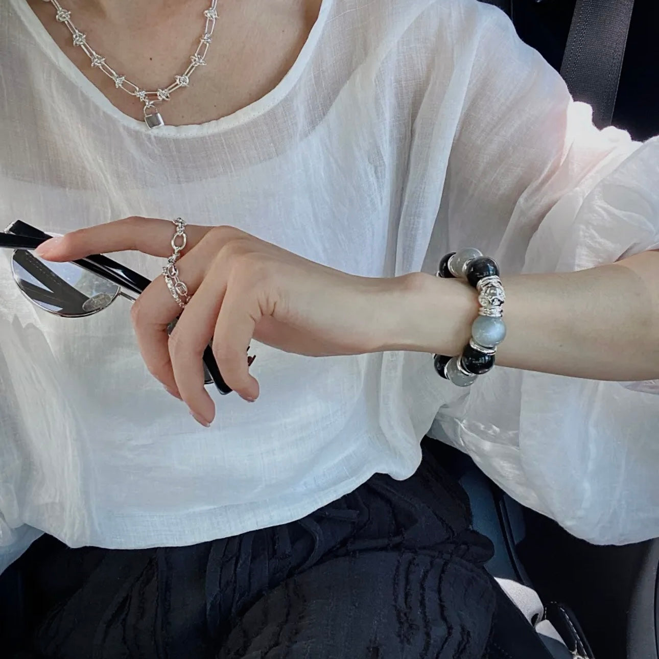 Close-up of a hand wearing a Silver White Moonstone and Silver Obsidian bracelet, highlighting natural gemstone textures and polished silver-toned details.