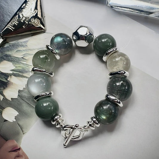Natural Green Rutile and Moonstone crystal bracelet featuring soft green and silver-gray gemstones styled in a minimalist flat lay.