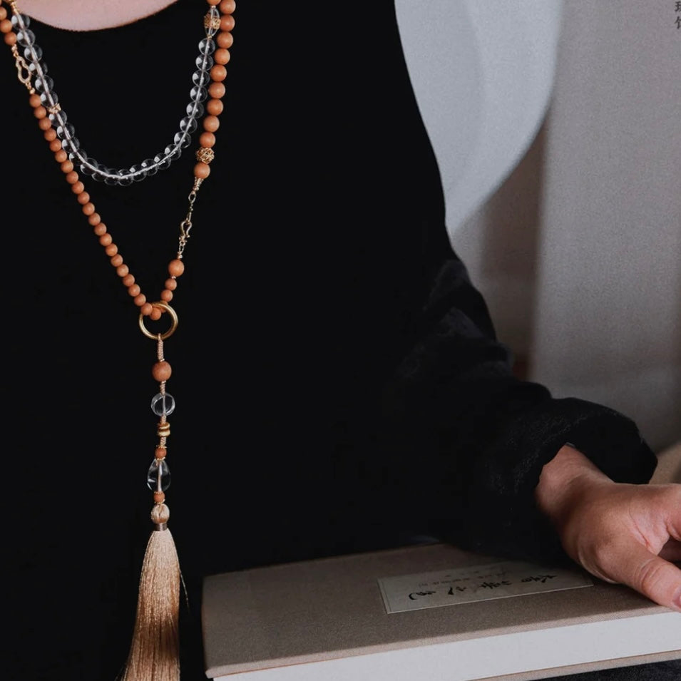 Detail shot of the natural sandalwood beads and delicate gold-toned connectors, releasing a faint elegant fragrance.