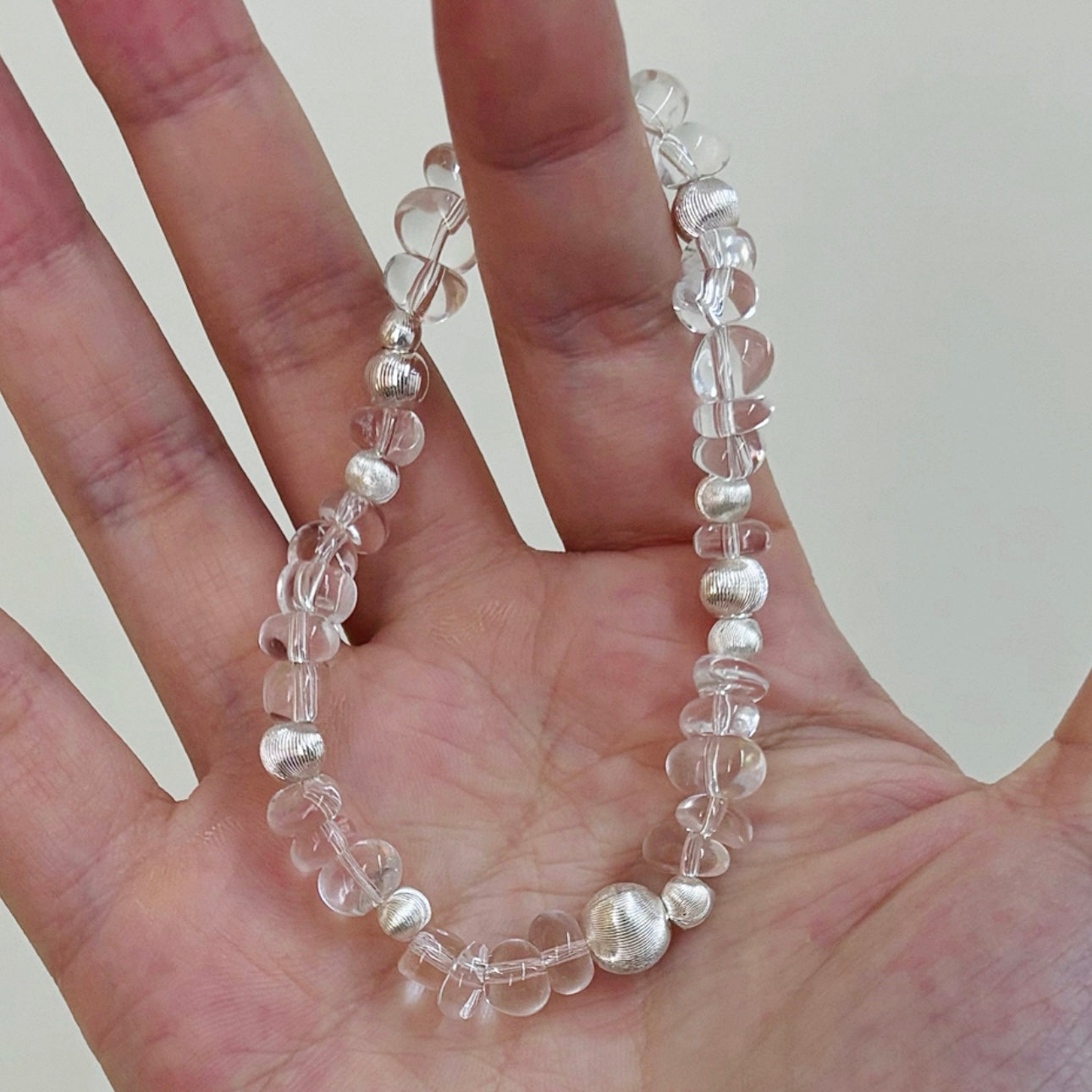 Close-up of a handmade white freeform clear quartz bracelet highlighting the natural shape, transparency, and polished silver-tone spacer beads.
