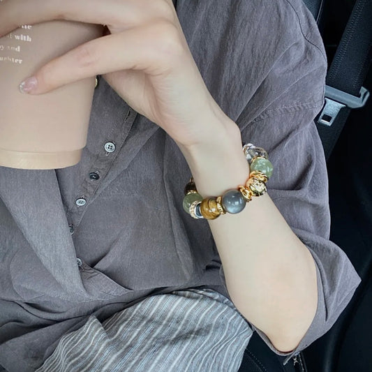 Hand model wearing chunky natural stone bracelet on wrist — green aventurine and smoky quartz beads, old money quiet luxury styling, everyday gemstone jewellery