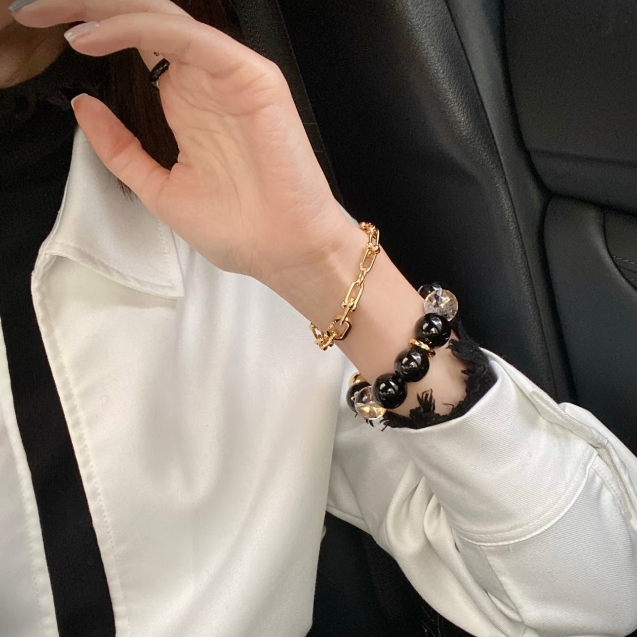 Model showcasing black obsidian and gold stone bead bracelet stacked with 24K gold titanium chain bracelet, elegant layered wrist jewelry