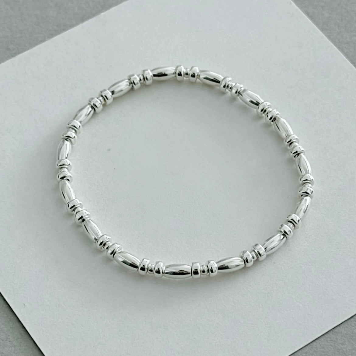 Close-up detail of S925 sterling silver rice bead bracelet — uniform small beads in slender 3mm chain design for delicate bracelet stacking