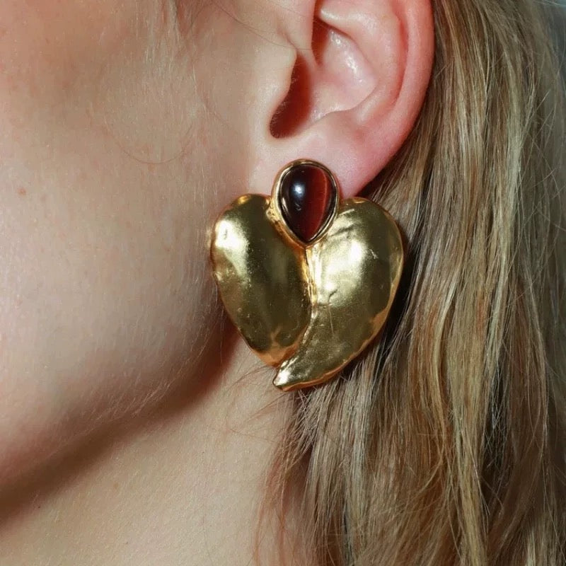 High-fashion model wearing oversized irregular gold petal studs with a bold, crumpled foil texture.
