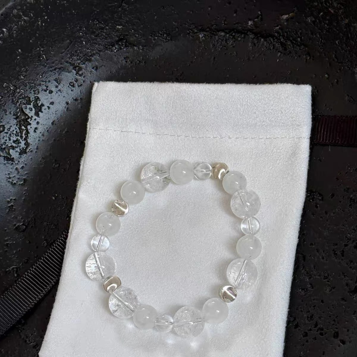 Close-up of snowflake white crystal beads showing milky diffused patterning alongside 6mm sterling silver cat's eye spacers — polished natural crystal bracelet bead detail