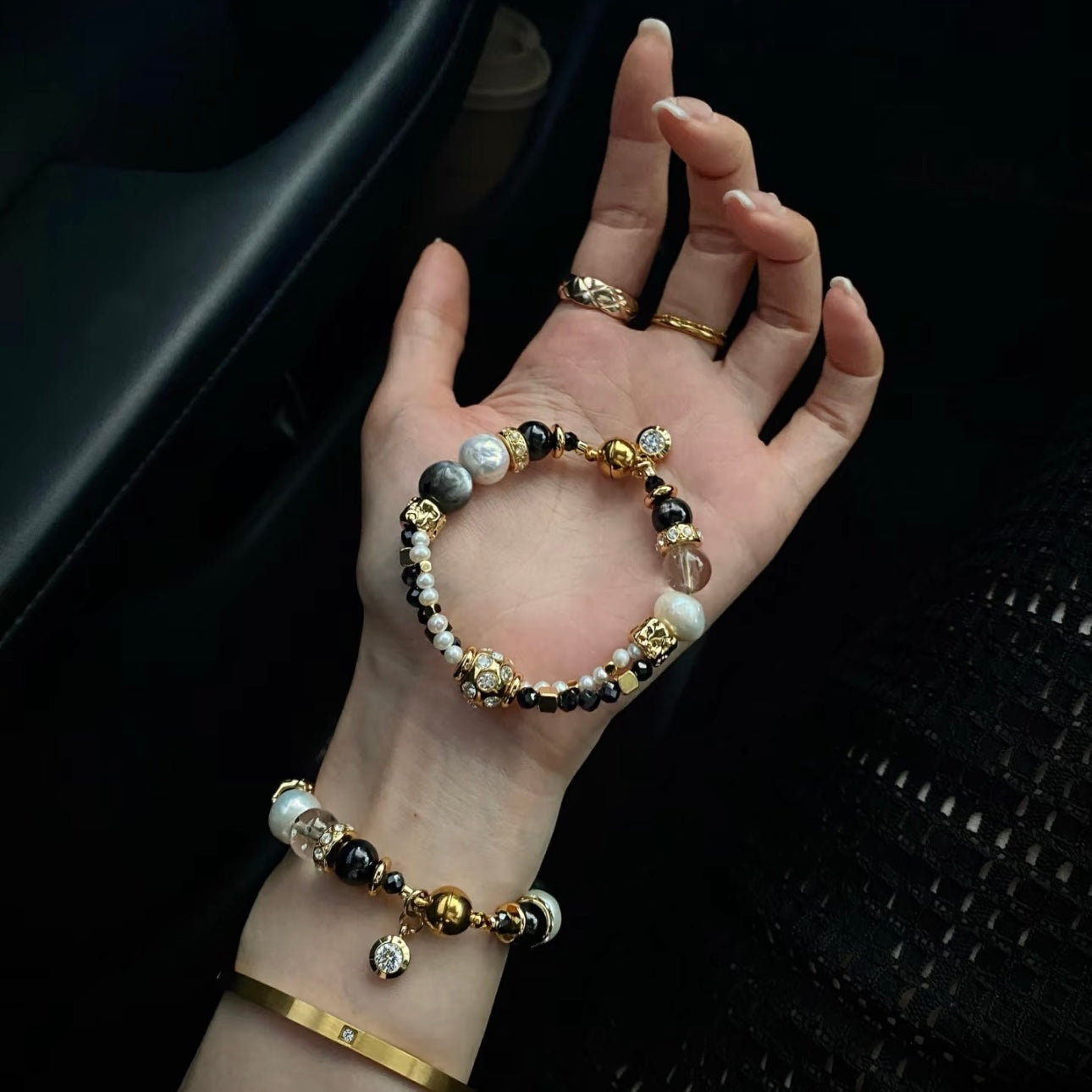 Starlight crystal bracelet stacked in Chanel-inspired black and gold jewelry look, iridescent quartz and pearl layering bracelet for designer style