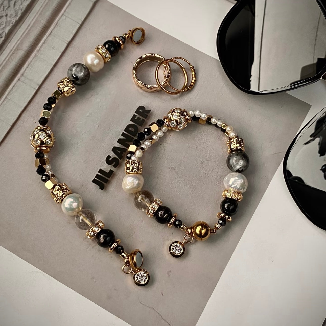 Close-up of Starlight Aura Quartz iridescent beads and 24K gold titanium clasp on layering bracelet, black and gold color palette