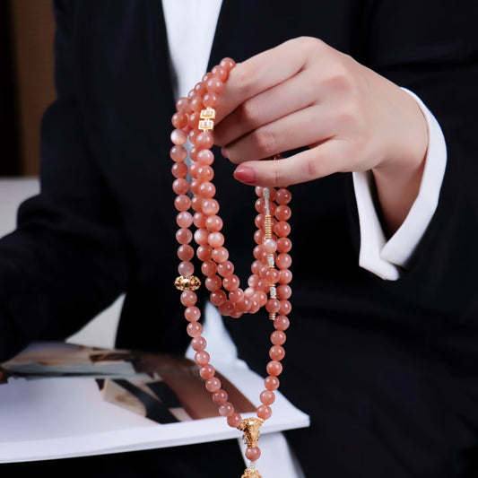 A model holding the Sunstone beads in natural light, showcasing the golden glitter surface and solar energy.