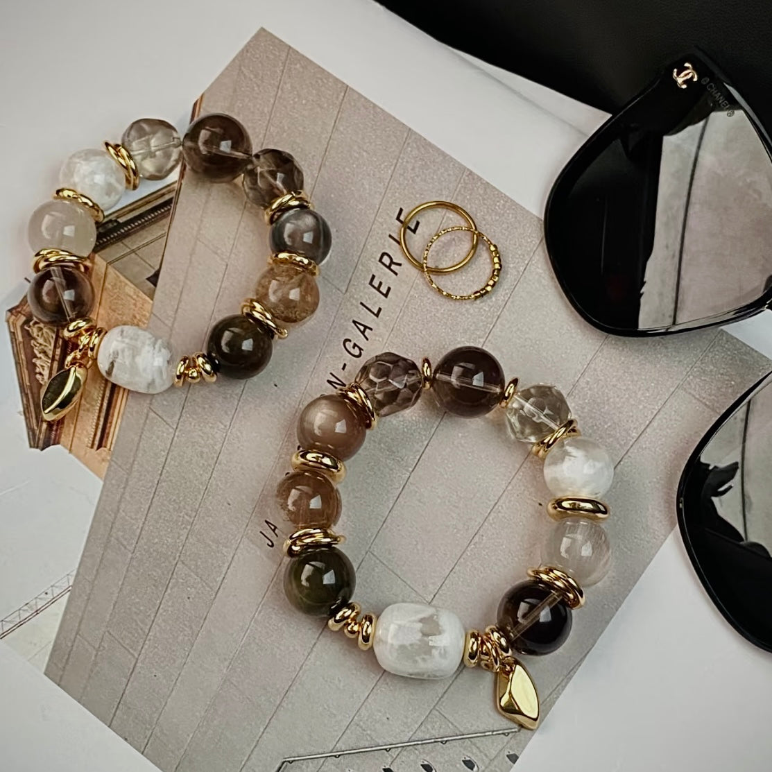 Vintage smoky quartz crystal bracelet with white snowflake phantom quartz and 24K gold hardware, flat lay