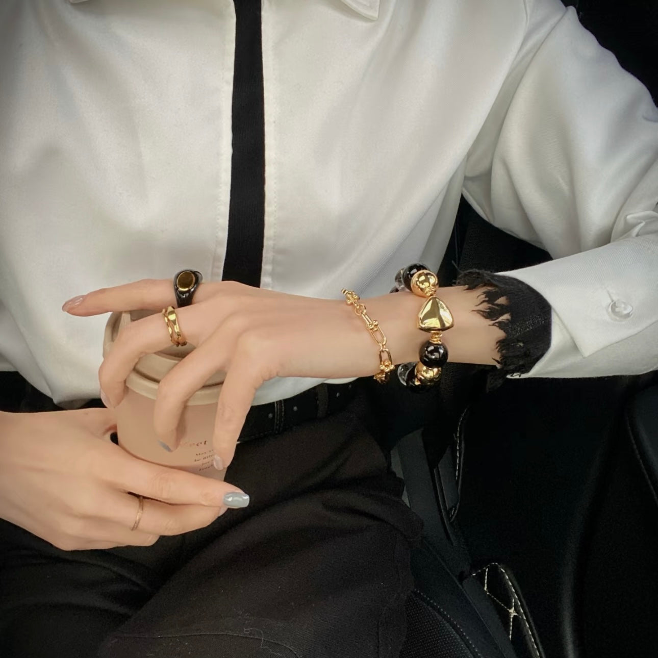 Woman wearing stacked black beaded bracelet and gold chain bracelet on wrist, layered crystal jewelry styling for powerful feminine energy 